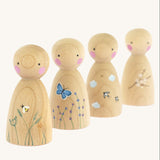 The Peepul Signs Of Spring Peg Doll Set stood one behind each other, are wooden with hand painted details. Each peg doll has a beautiful spring design, and from left to right is a bee flying above grass, a butterfly fling above flowers, swallows flying in the clouds, and a branch of white flowers delicately painted on the peg doll. The image is on a cream background
