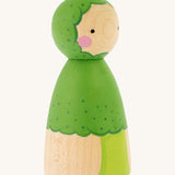 The side of the Peepul Broccoli Peg Doll, is a beautiful, hand painted peg doll with a green broccoli stem and floret body, a green painted broccoli  hood. The image is on a cream background