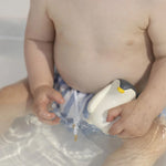 A child playing with the Oli &amp; Carol Penguin Bath Toy in a bath