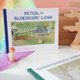 Peter in Blueberry Land children's hardback book by Elsa Beskow on shelf next to another book from the series, Christopher's Garden.