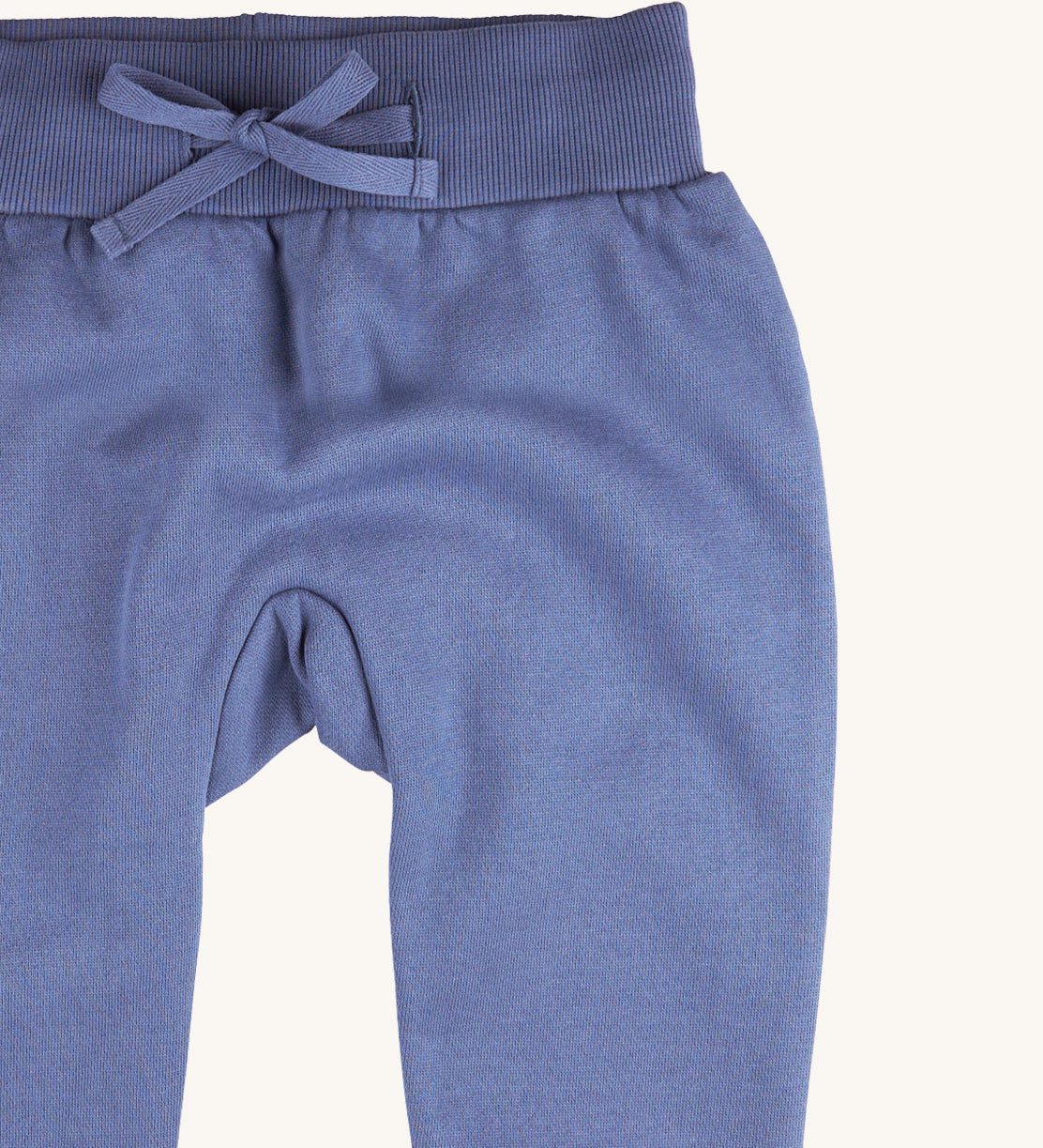 A close up of the Pigeon Organics blue sweatpants  available at Babipur showing the drawstring and elasticated waistband detail 