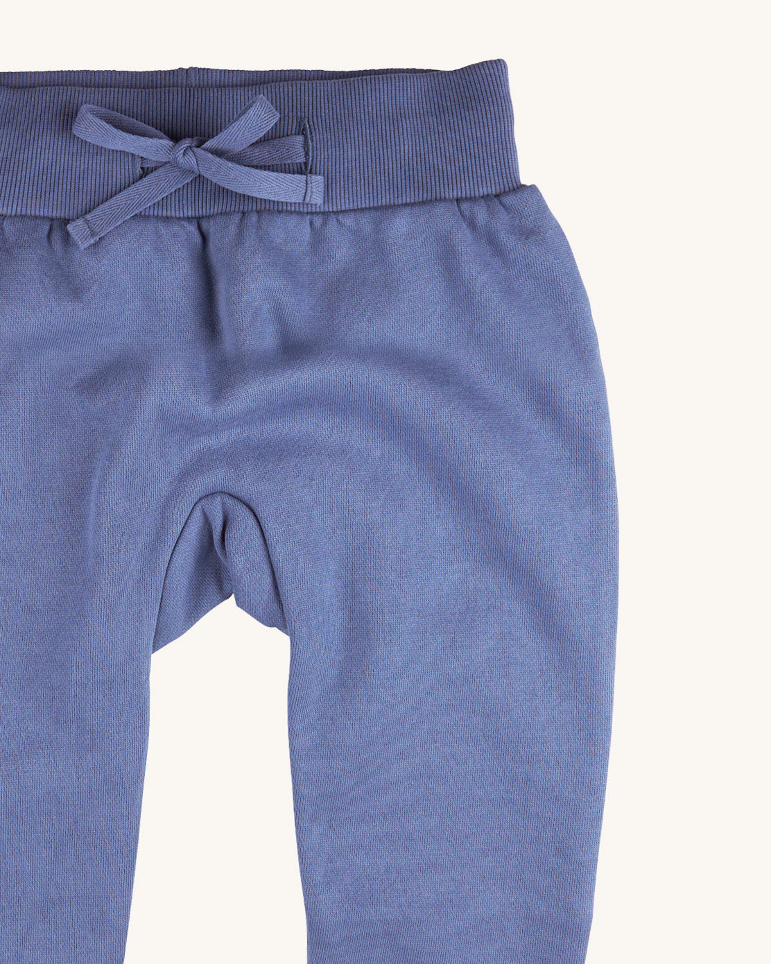 A close up of the Pigeon Organics blue sweatpants  available at Babipur showing the drawstring and elasticated waistband detail 