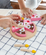 Children playing with the PlanToys wooden birthday cake set with loose candles on a table 