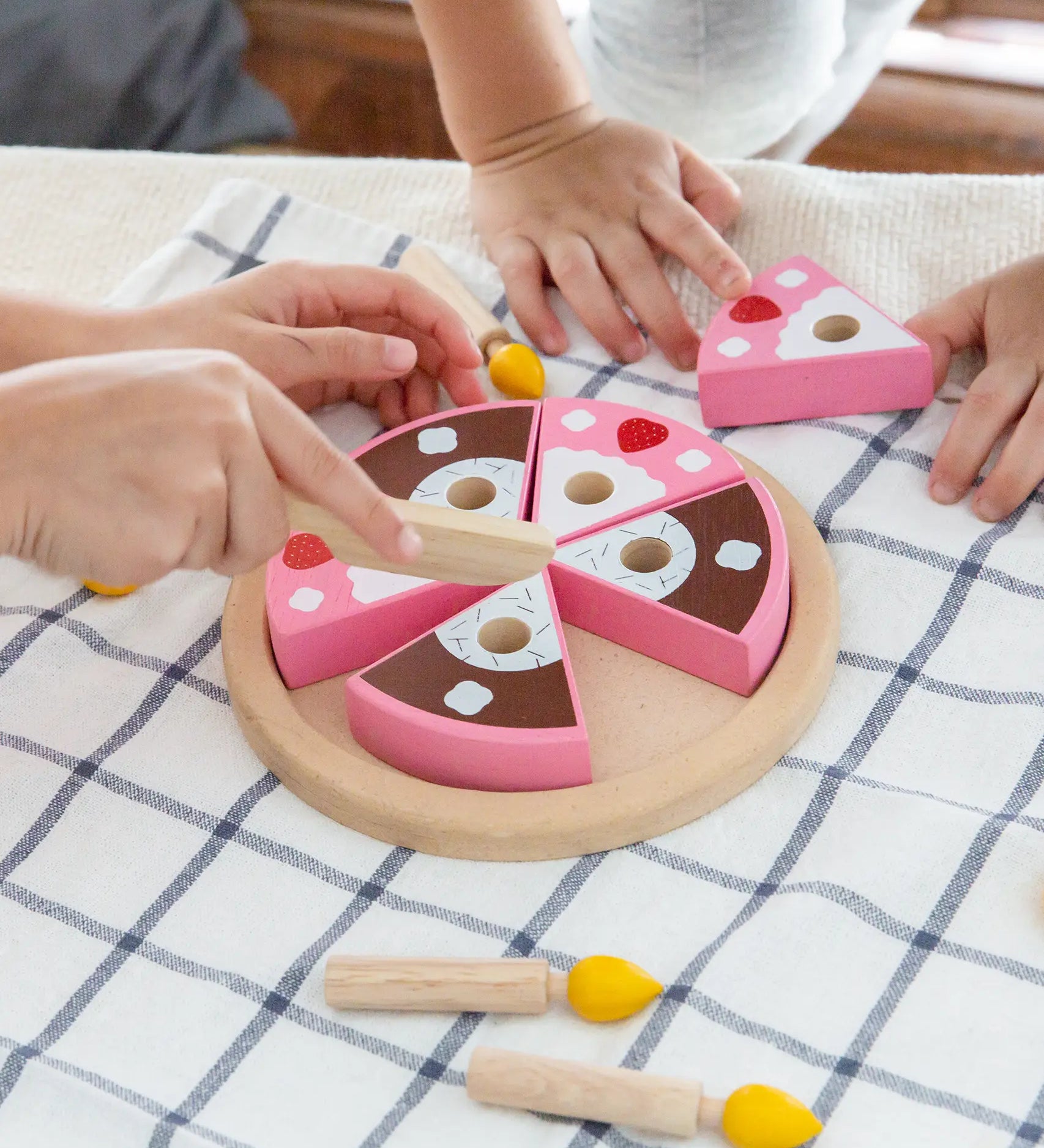 Children playing with the PlanToys wooden birthday cake set with loose candles on a table 