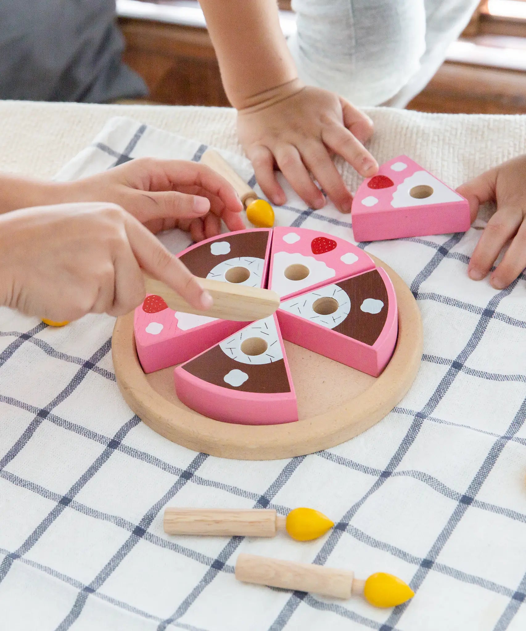 Children playing with the PlanToys wooden birthday cake set with loose candles on a table 