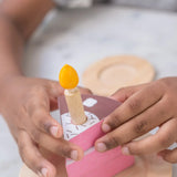 PlanToys birthday wooden cake set showing a close up a child with a single slice and candle 