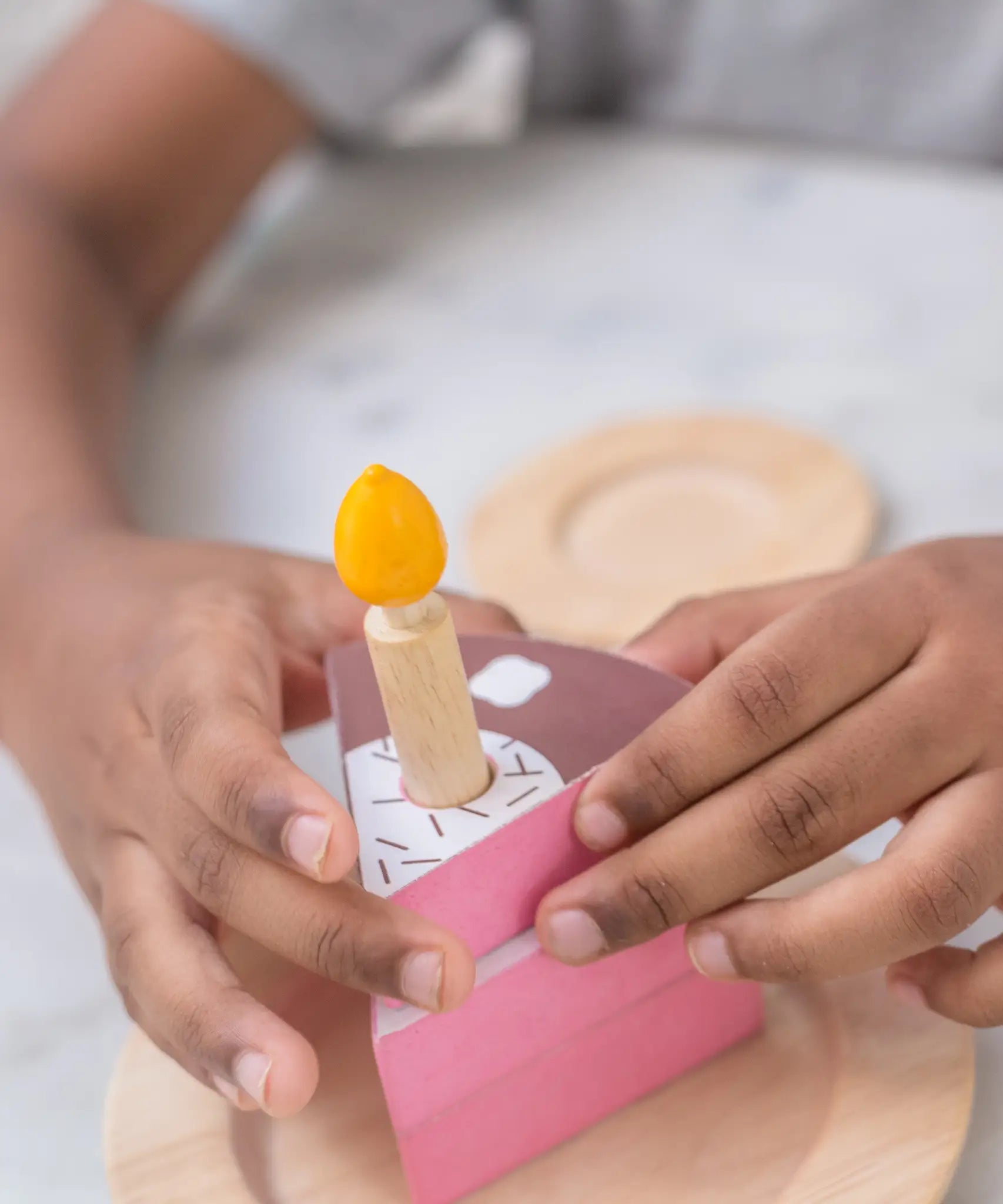 PlanToys birthday wooden cake set showing a close up a child with a single slice and candle 