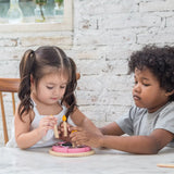 Children putting on pretend candle on the PlanToys birthday cake set 
