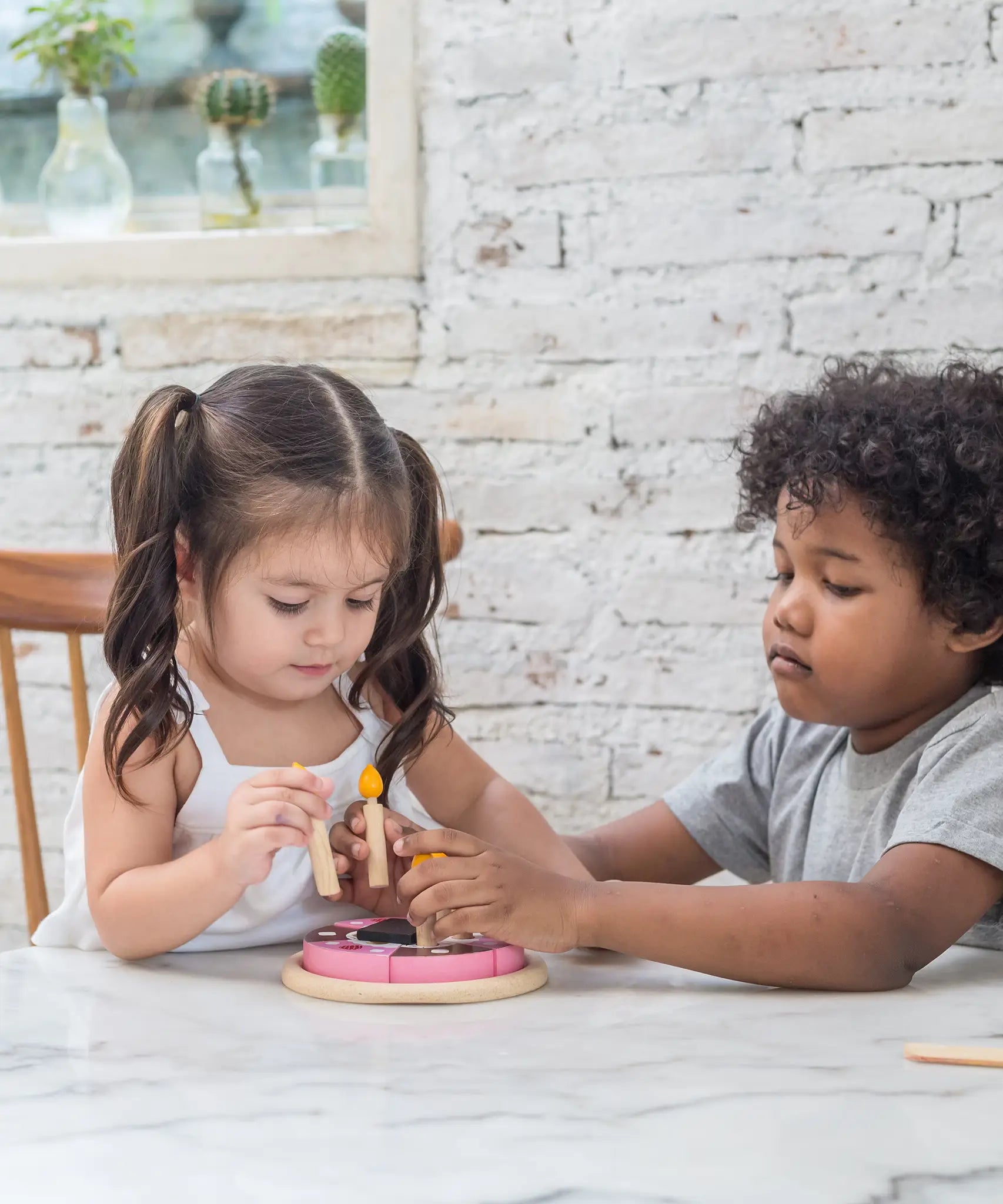 Children putting on pretend candle on the PlanToys birthday cake set 