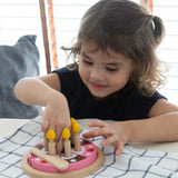 Child playing with the PlanToys wooden birthday cake set with wooden candles inside the holes