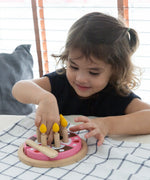 Child playing with the PlanToys wooden birthday cake set with wooden candles inside the holes