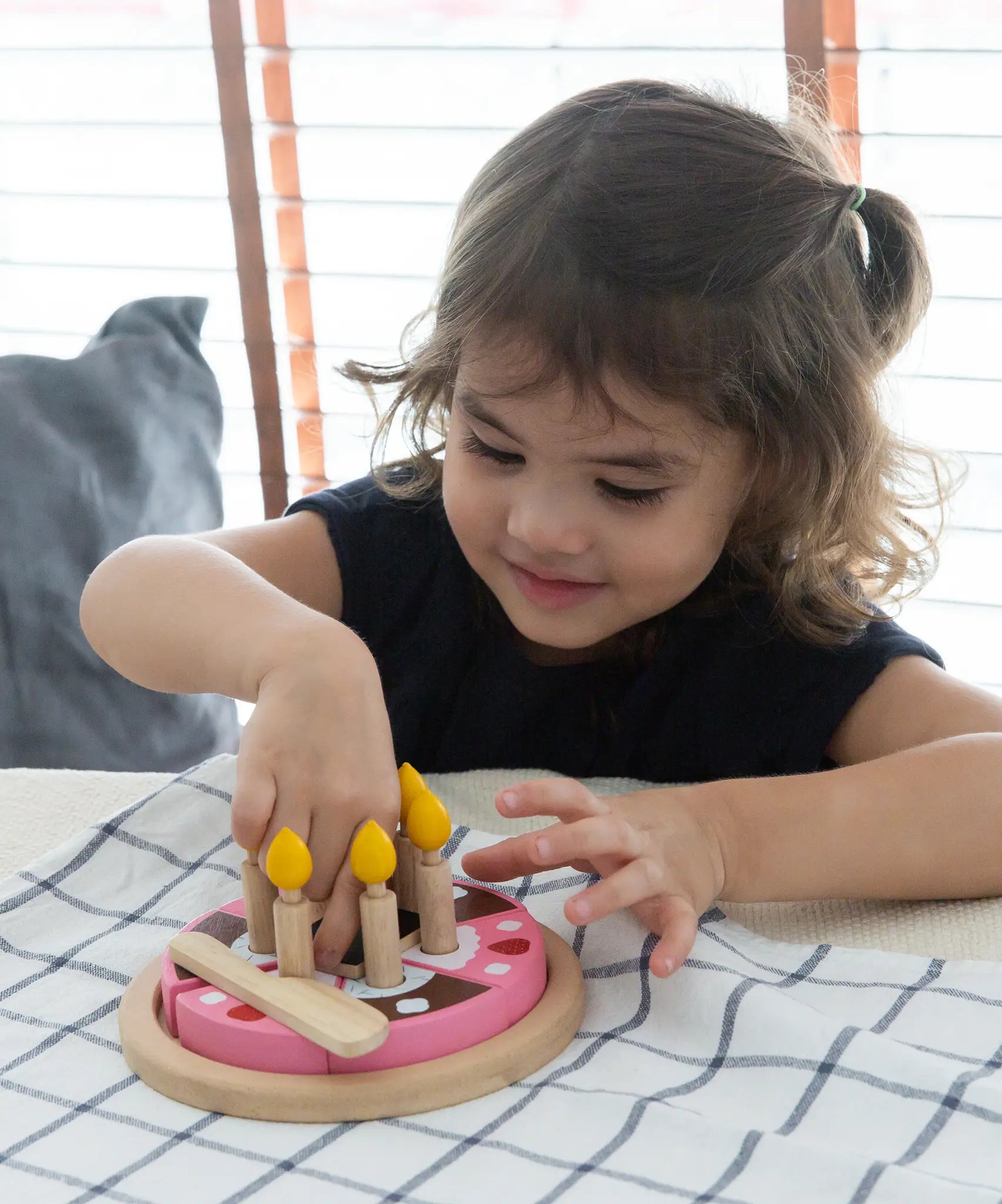 Child playing with the PlanToys wooden birthday cake set with wooden candles inside the holes