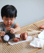 Child playing with the loose pieces from the PlanToys bread loaf play set on a table