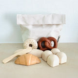PlanToys bread play set on a table showing a cotton bag, bread rolls, pastries and a wooden knife