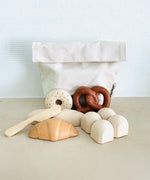 PlanToys bread play set on a table showing a cotton bag, bread rolls, pastries and a wooden knife