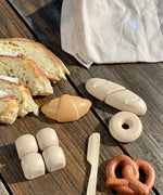 Loose play food pieces next to the cotton bag from the PlanToys bread play set