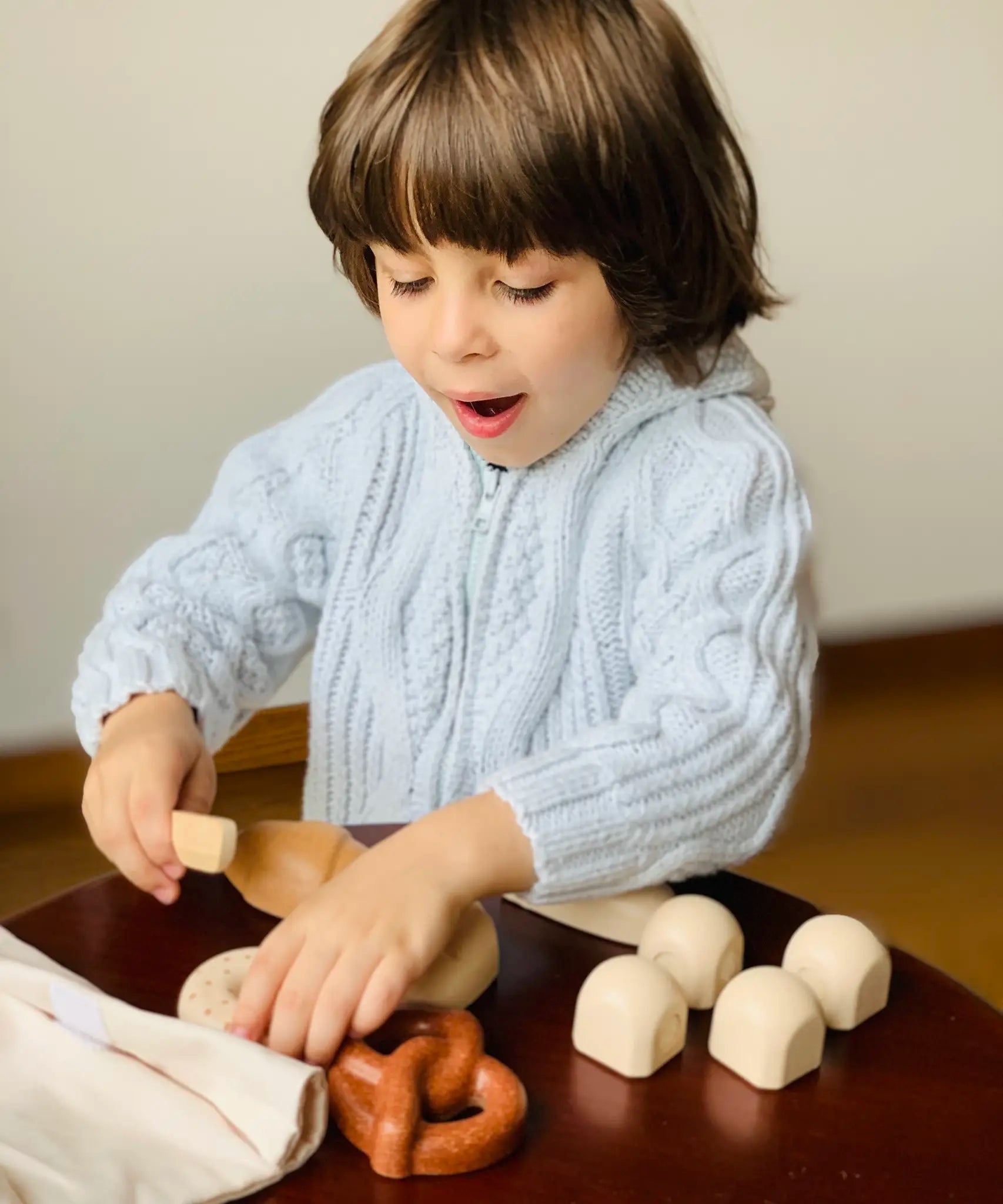 Child playing with a pretend pastry from the PlanToys bread play set