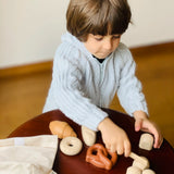 Child playing with pretend rolls from the PlanToys bread play set