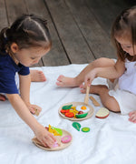 Children playing with different play wood pieces from the PlanToys breakfast menu set