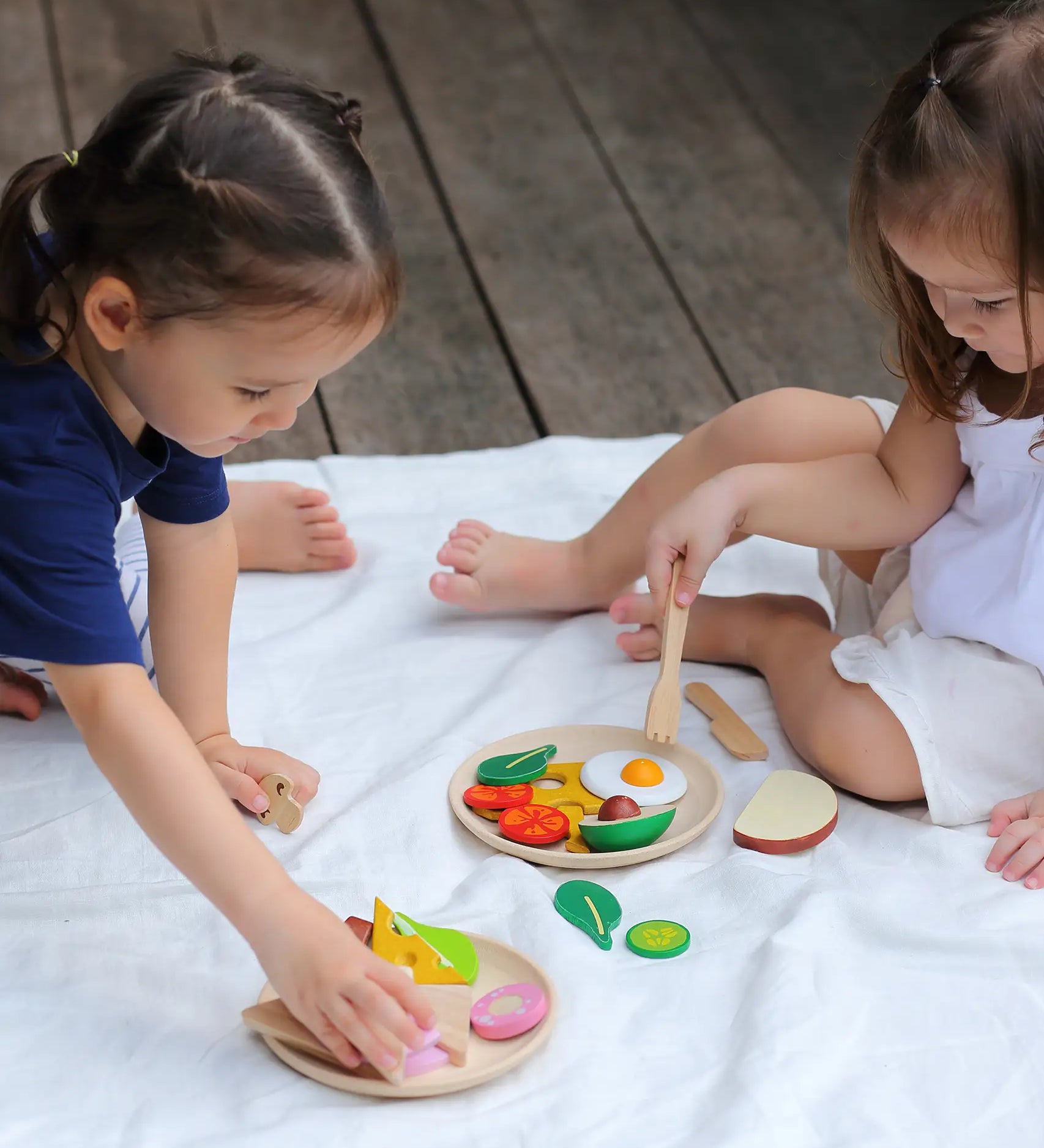Children playing with different play wood pieces from the PlanToys breakfast menu set