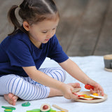 Child making a sandwich from different play food pieces from the Plan Toys breakfast menu play set