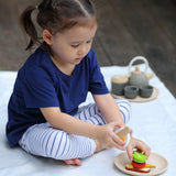 Child making a sandwich from different play food pieces from the PlanToys breakfast menu set