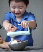 Child holding on the working mixer from the PlanToys cake mixer play set on a bowl