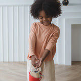 Child carrying a red bucket from the Plantoys cleaning set filled with tools