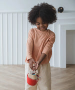 Child carrying a red bucket from the Plantoys cleaning set filled with tools