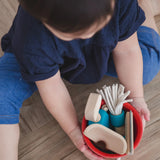 Overhead view of a child holding onto the red bucket from the PlanToys cleaning set filled with tools 