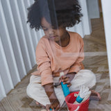 Child cleaning a window using the tools from the PlanToys cleaning set