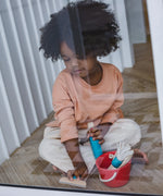 Child cleaning a window using the tools from the PlanToys cleaning set
