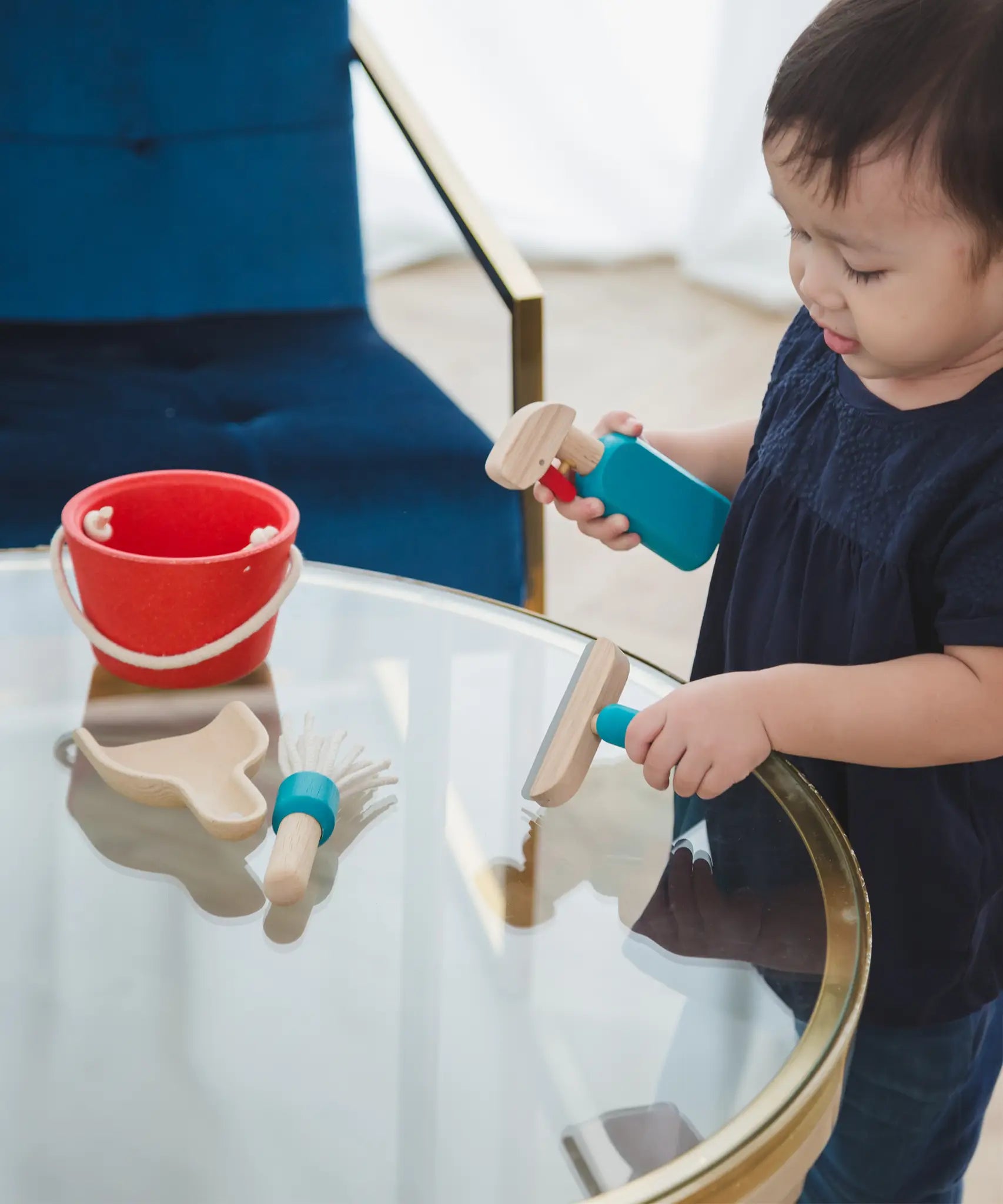 Child cleaning a table using tools from the PlanToys cleaning set
