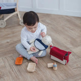 Child with a teddy bear wearing a bib from the PlanToys feeding set