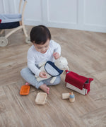 Child with a teddy bear wearing a bib from the PlanToys feeding set