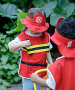 A child reaching for a walkie talkie inside a pocket on vest from the PlanToys fire fighter pretend play set