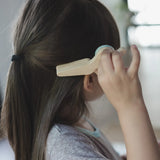 Child holding a pair of wooden scissors from the PlanToys hair dresser set showing scale