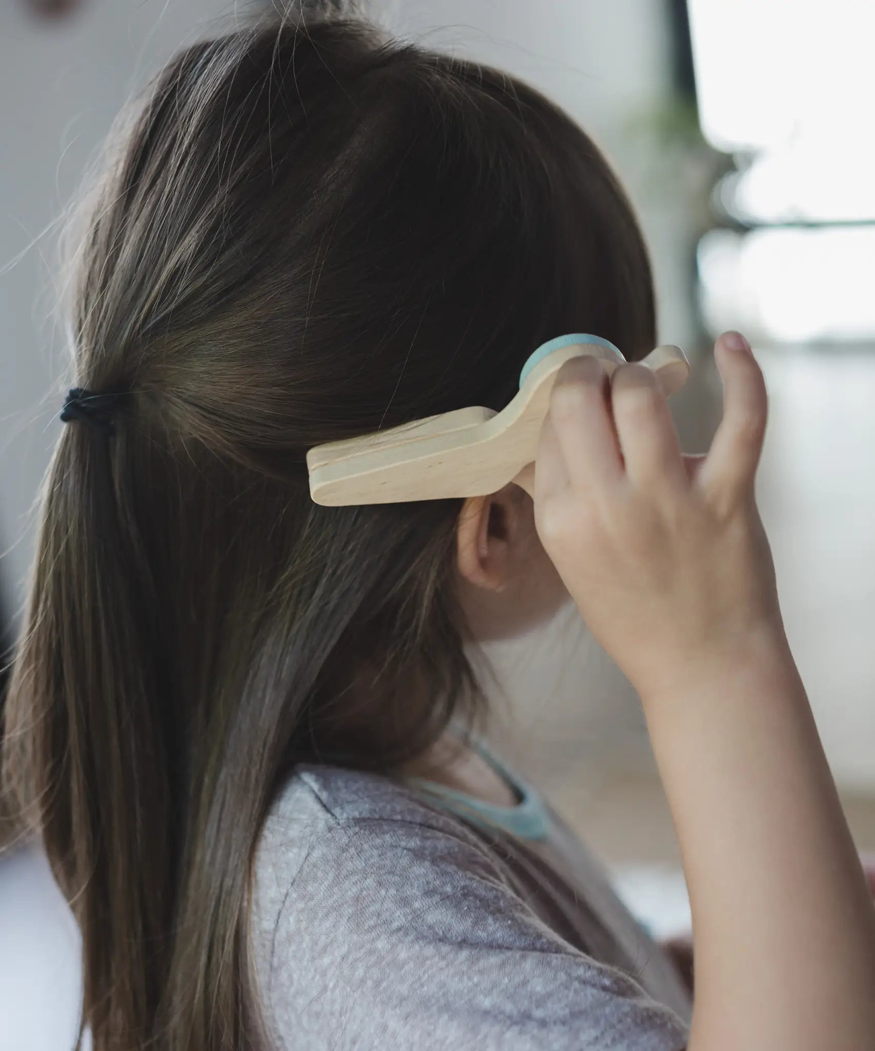 Child holding a pair of wooden scissors from the PlanToys hair dresser set showing scale