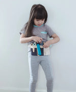 Child wearing the waist bag with accessories from the Plan Toys hair dresser set 