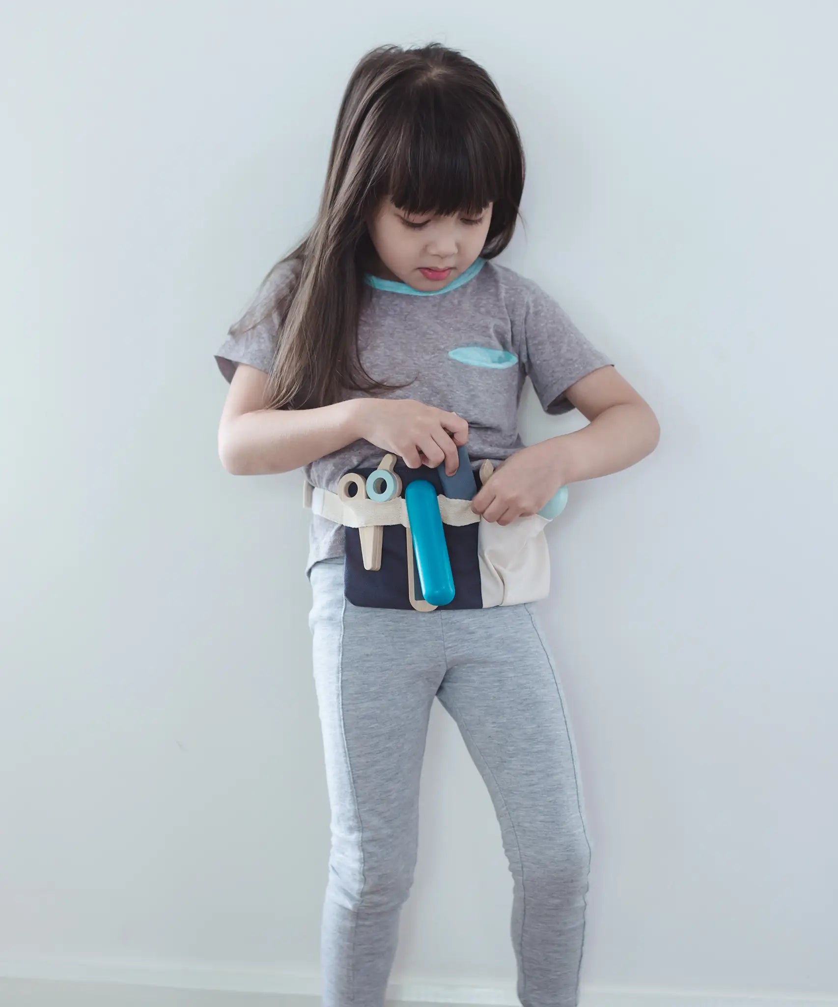 Child wearing the waist bag with accessories from the Plan Toys hair dresser set 
