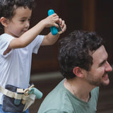 Child with a PlanToys hair dresser set waist bag with accessories and holding hair straighteners. 