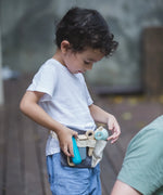 Child wearing the waist bag from the PlanToys hair dresser set with different accessories 
