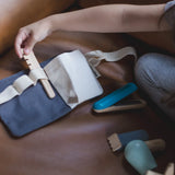 Plan Toys hair dresser waist bag laid flat with a child reaching for a hair brush