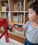 A close up of a child playing with the drill from the Plan Toys wooden handy carpenter set available at Babipur