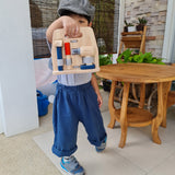 A child holding the Plan Toys wooden handy carpenter set tool stand showing the hammer, chisel and drill. Role play set available at Babipur