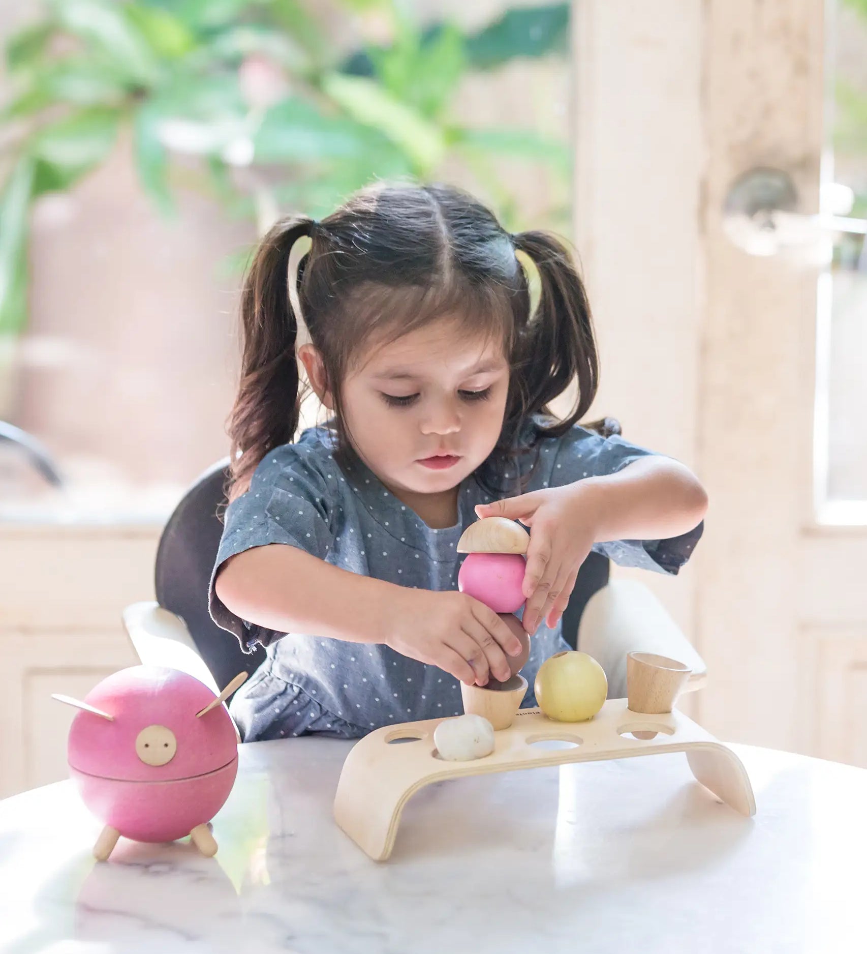 Child stacking different coloured ice cream scoops from the PlanToys wooden ice cream play set