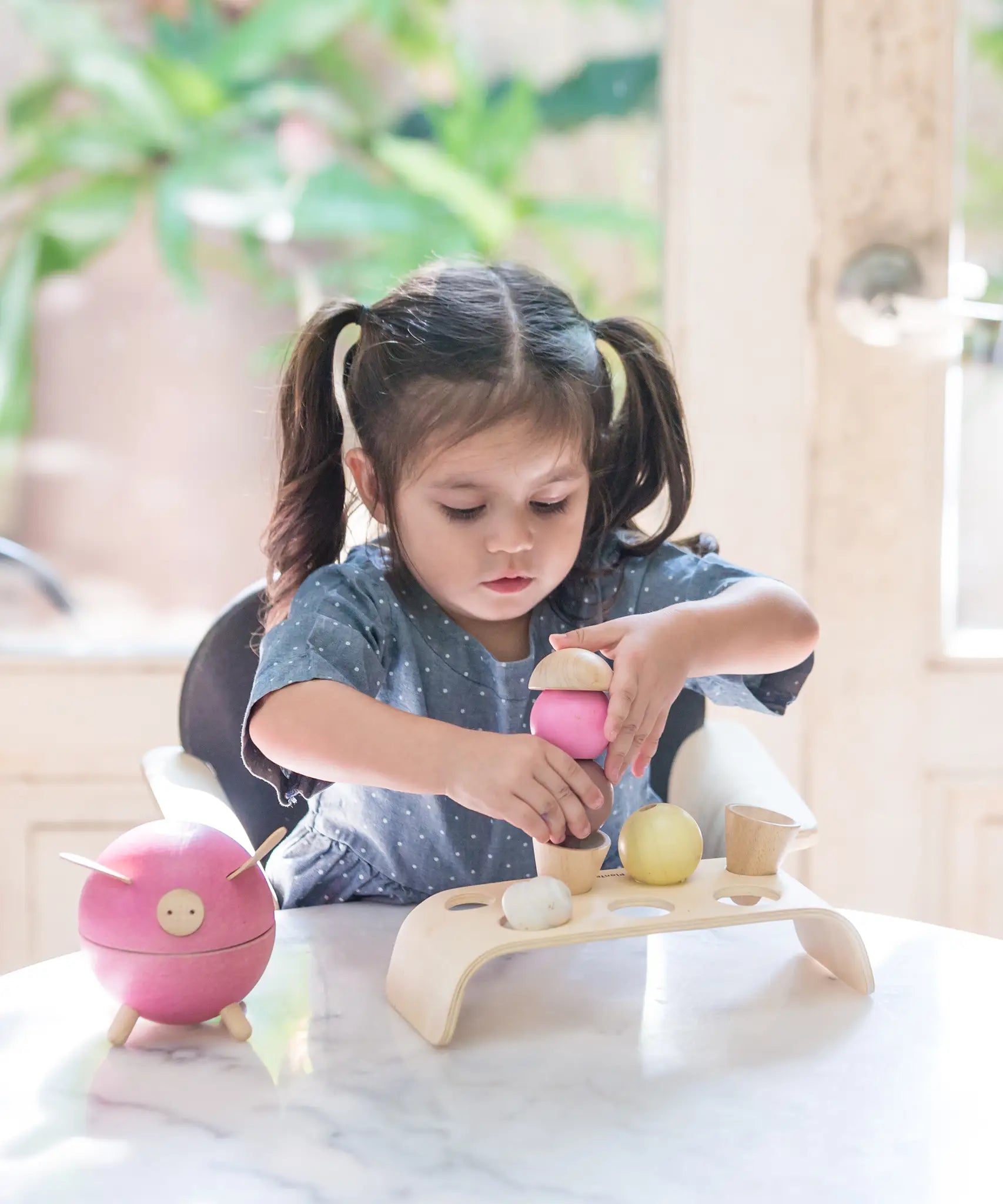 Child stacking different coloured ice cream scoops from the PlanToys wooden ice cream play set