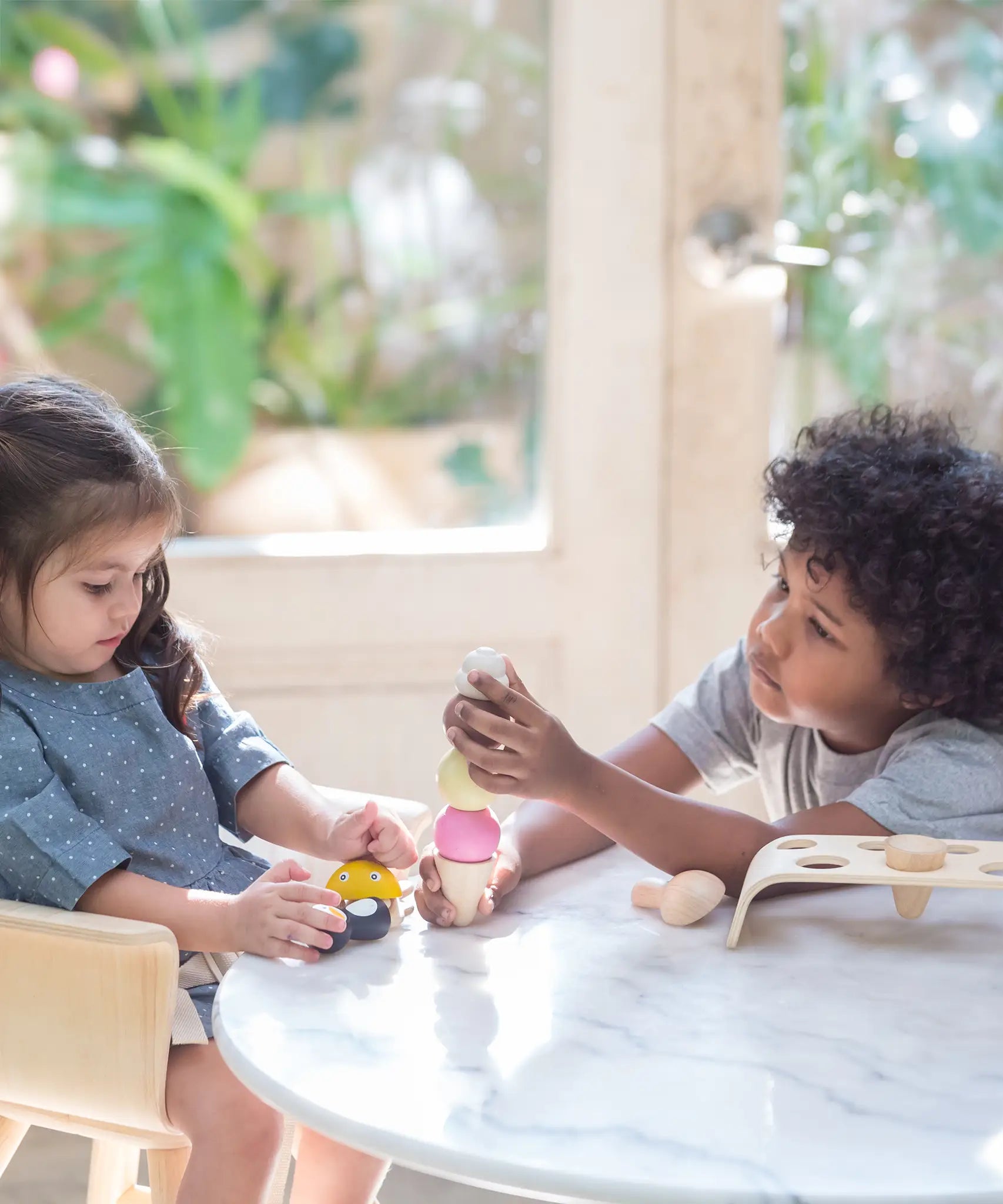 Children playing with the PlanToys wooden ice cream play set
