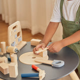 A close up of a child using the ruler from the Plan Toys wooden handy carpenter set available at Babipur with the other tools standing on a wooden Plan Toys table