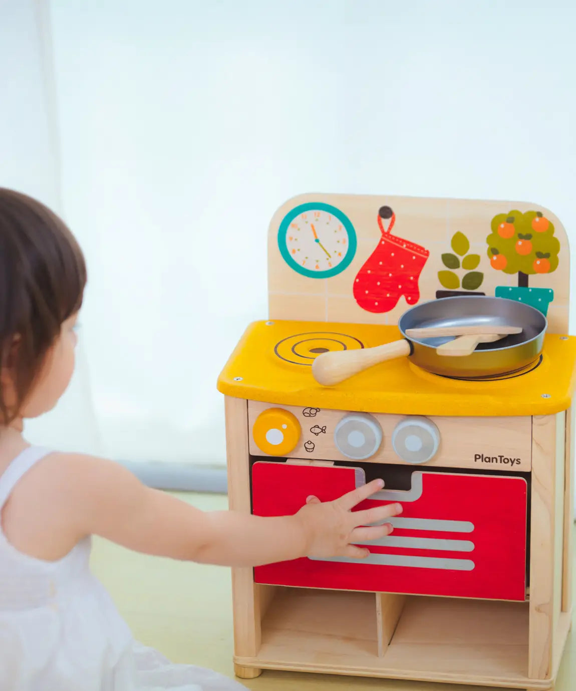 Child closing the oven door on the PlanToys kitchen set